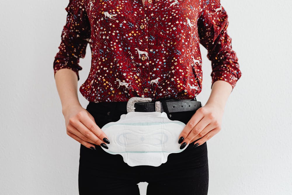 Organic sanitary pads: A person in a patterned blouse holds a sanitary pad against their waist, showcasing a casual, relatable moment.